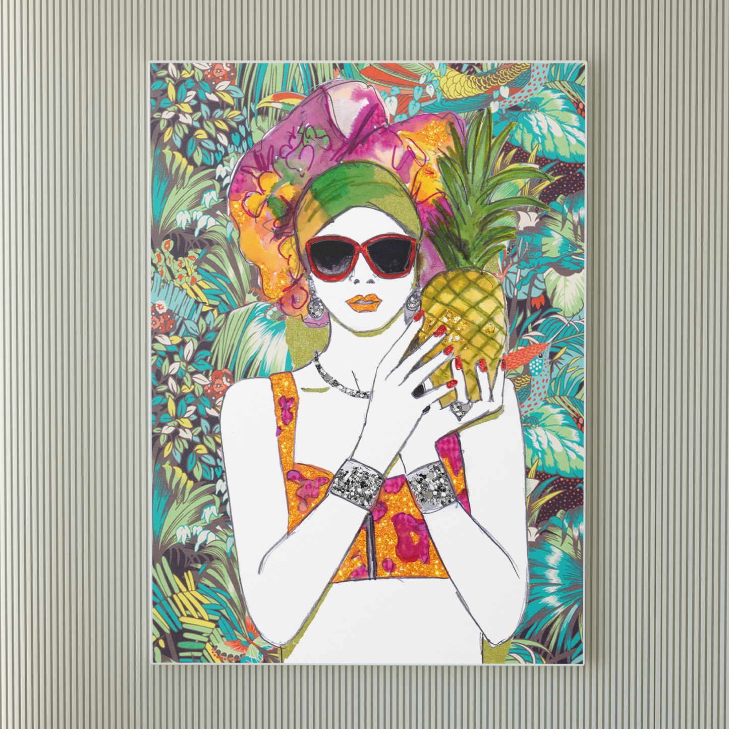 Image shows a framed illustration of a woman holding a pineapple with a colourful head wrap and a bright, tropical, collage background