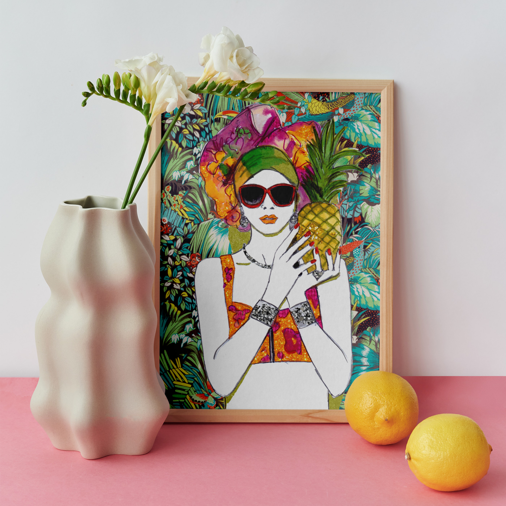 Image shows a framed illustration of a woman holding a pineapple with a colourful head wrap and a bright, tropical, collage background