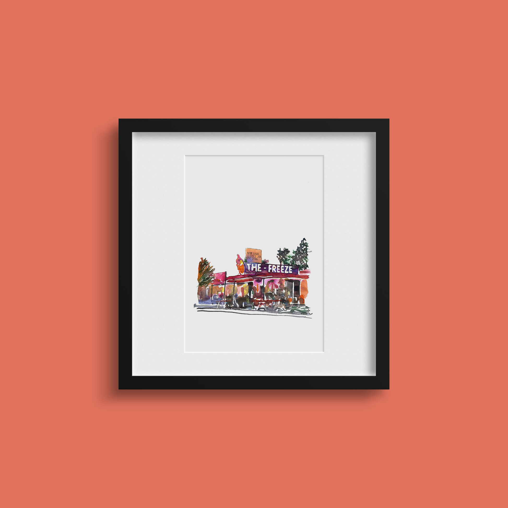 Framed artwork of a building with 'The Freeze' sign on an orange wall