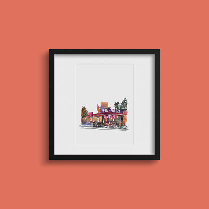 Framed artwork of a building with 'The Freeze' sign on an orange wall