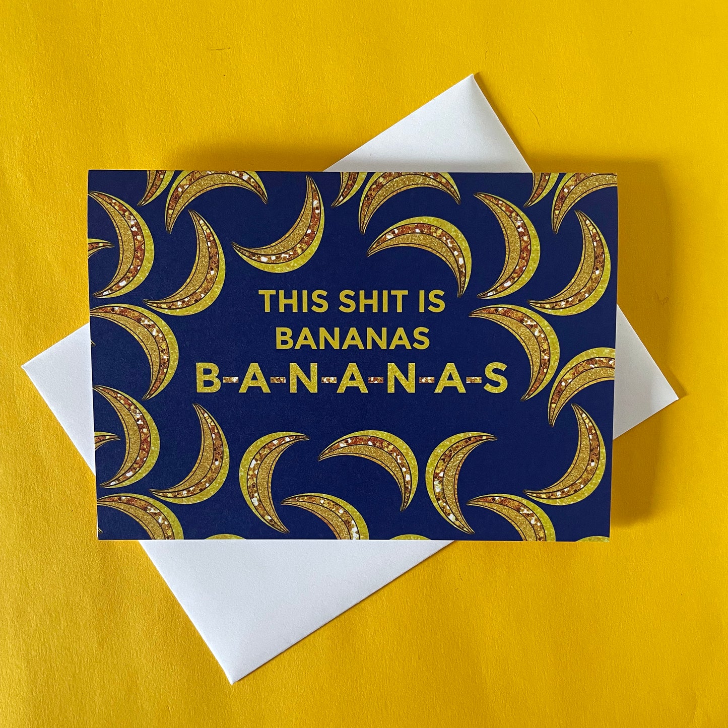Image of a blue card on a bright yellow background. The card features bejewelled illustrations of bananas and the message 'This Shit is Bananas B-A-N-A-N-A-S.