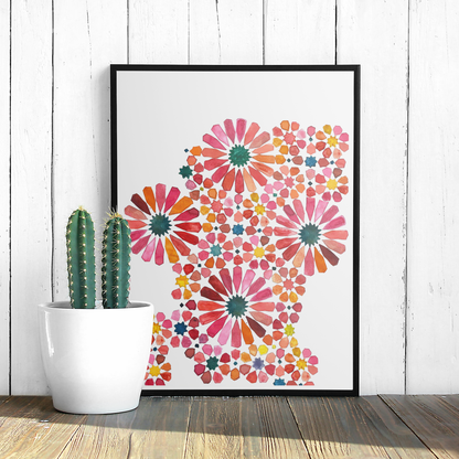 Framed colourful floral art print on a white wall with a cactus plant.
