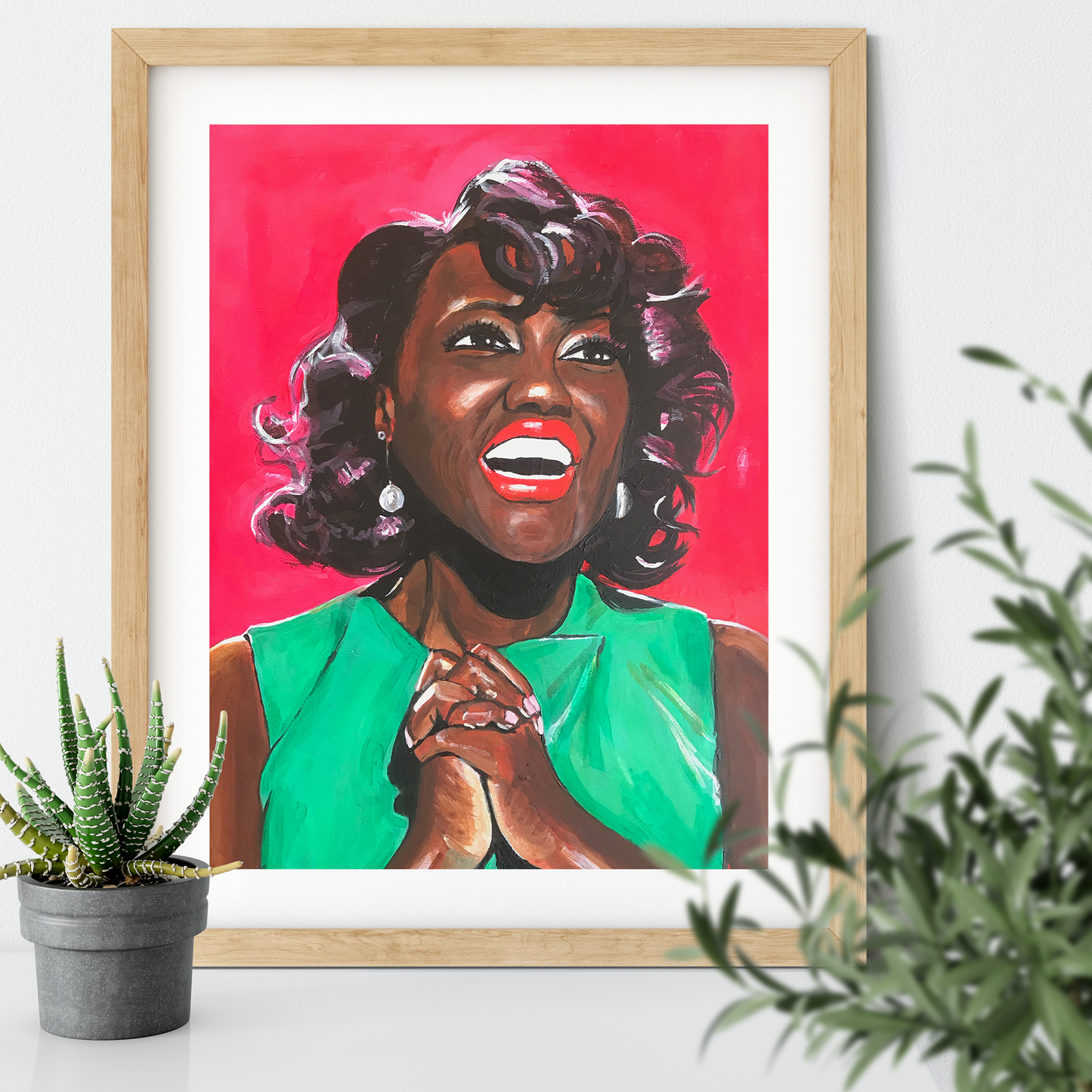 Image shows a joyful portrait of Viola Davis wearing a bright green dress, clasping her hands together and smiling on a bright pink background