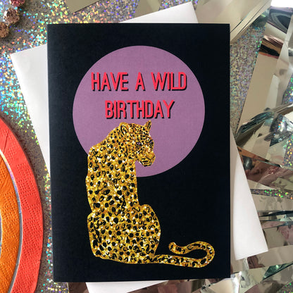 Wild birthday card featuring a gold glitter leopard in front of a lilac full moon.Wild birthday card featuring a gold glitter leopard in front of a lilac full moon.