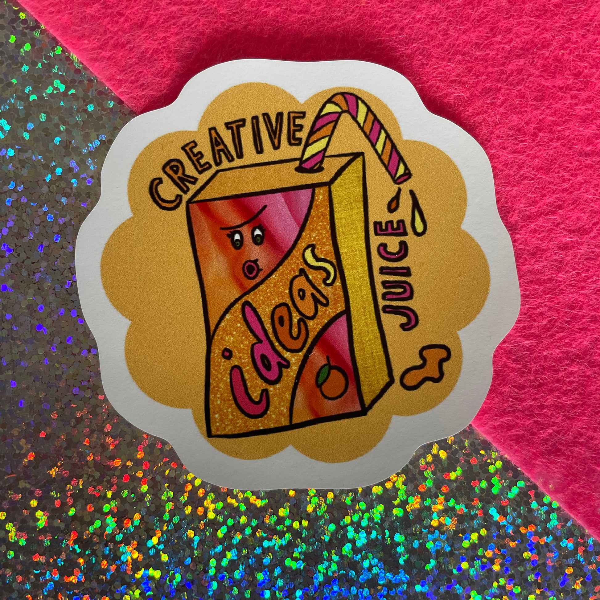 Image shows a bright yellowy orange flower shaped sticker with a colourful illustration of a juice carton with straw and the words 'Creative Juice'