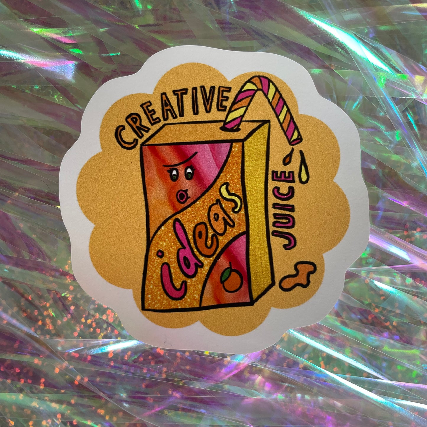 Image shows a bright yellowy orange flower shaped sticker with a colourful illustration of a juice carton with straw and the words 'Creative Juice'